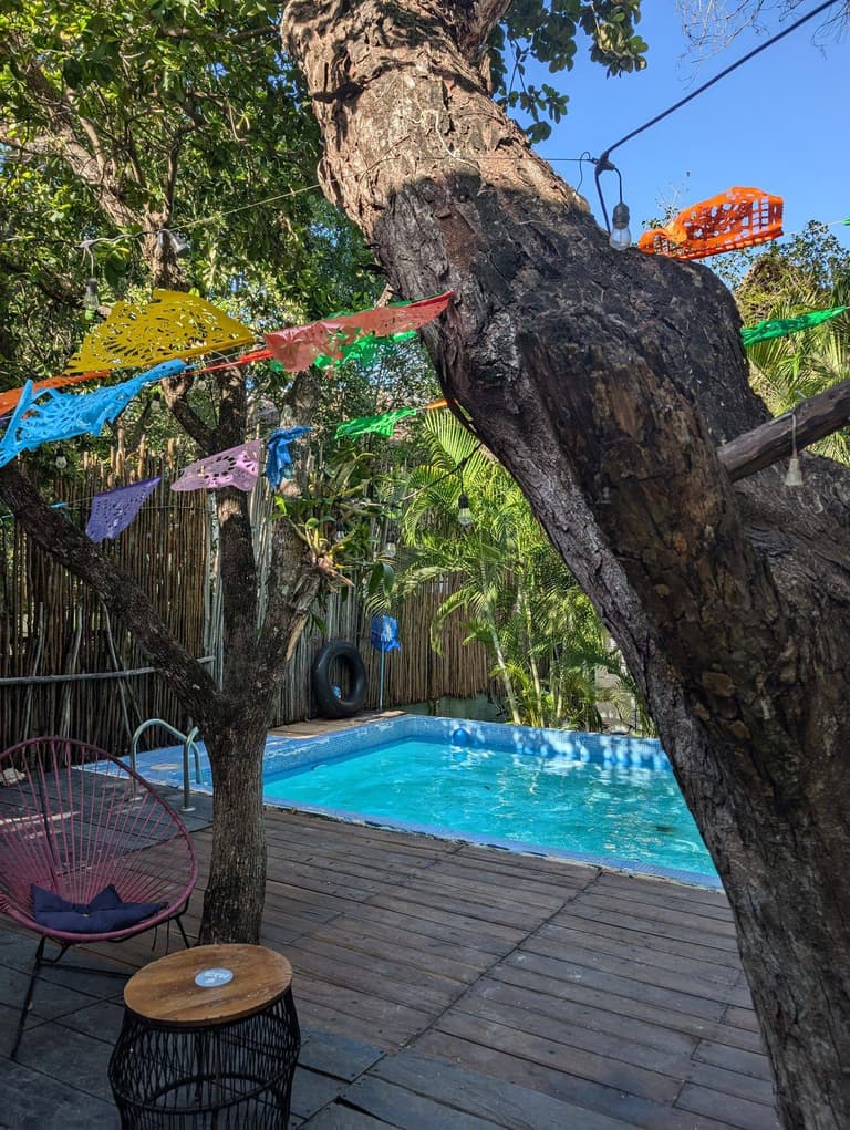 Friends hanging at the jungle pool with papel picado flags — Maui Hostels Tulum